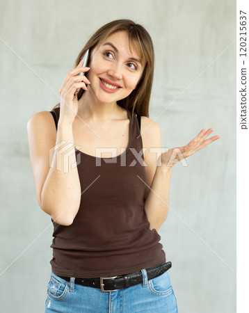 Young cheerful woman with wide grin on her face talking on phone Young cheerful woman with wide grin on her face talking on phone 120215637