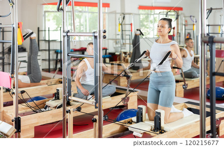 Young girl doing arm exercises on cable reformer device 120215677