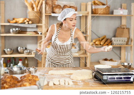 Woman baker cuts and weighs pieces of dough 120215755