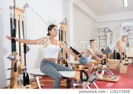 Young woman training her arms using straps Young woman training her arms using straps 120215808