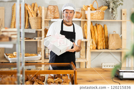 Middle-aged salesman holding cake box in bakery 120215836