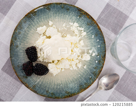 Cottage cheese with cream and fresh blackberries on plate 120215885