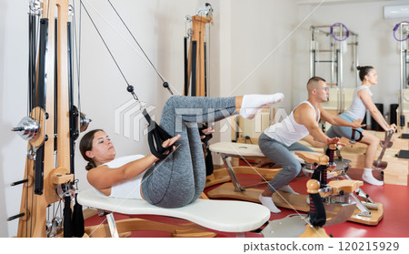 Active young woman doing press exercises on cable training device 120215929
