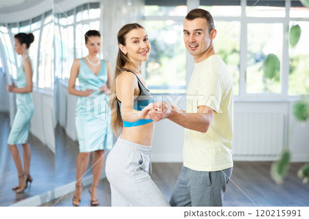 Positive man and woman practicing samba in dance class 120215991