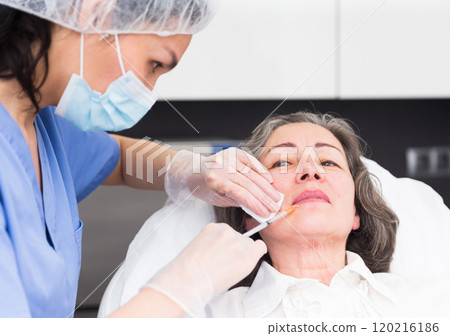 Plastic surgeon preparing for operation on woman face 120216186