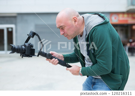 Videographer recording video on site with mirrorless camera using gimbal Videographer recording video on site with mirrorless camera using gimbal 120216311