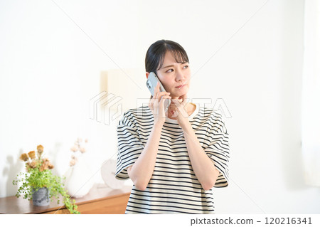 Young woman making a phone call in the living room, living room, one-room apartment 120216341