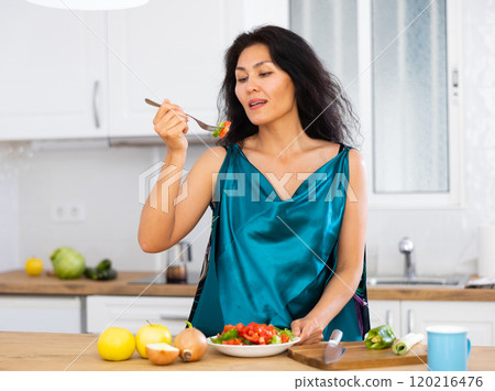 Portrait of woman eating salad at home 120216476