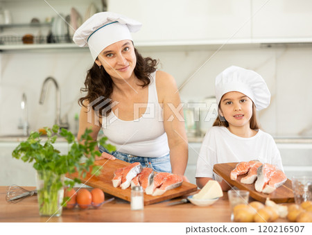 Happy mother and her daughter preparing salmon to bake in the kitchen 120216507