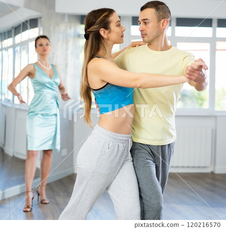 Couple in comfortable sports clothes waltz dancing during individual lesson 120216570
