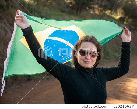 Smiling woman holding large flag of Brazil Smiling woman holding large flag of Brazil 120216657