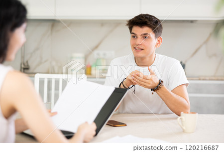 Young guy discussing deal with saleswoman in kitchen Young guy discussing deal with saleswoman in kitchen 120216687