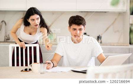 Young woman quarrels with young guy working at laptop Young woman quarrels with young guy working at laptop 120216694
