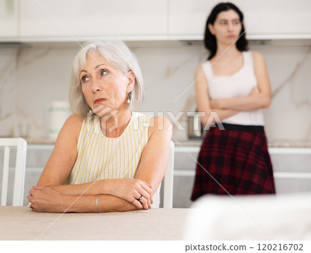 Young woman quarrels with elderly woman in kitchen Young woman quarrels with elderly woman in kitchen 120216702