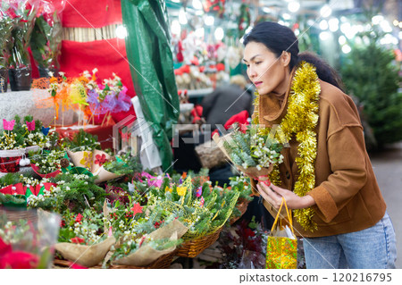 Woman choosing christmas decoration at street fair Woman choosing christmas decoration at street fair 120216795
