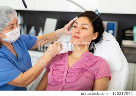 Woman getting injection for facial correction procedure in clinic 120217045