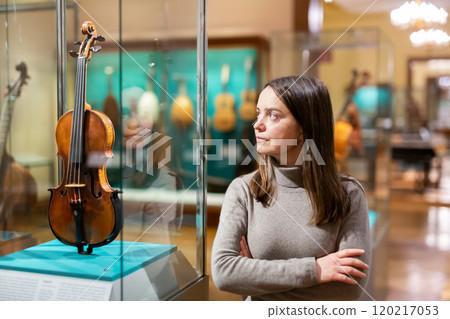 Female museum visitor examining ancient musical instruments 120217053