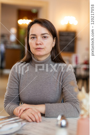 Brunette sitting in cozy cafe with cup of coffee Brunette sitting in cozy cafe with cup of coffee 120217058