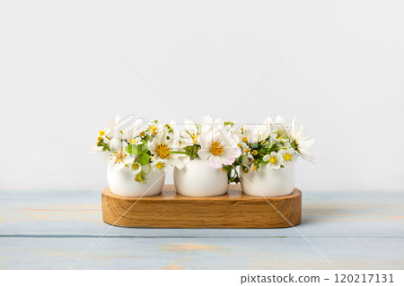 White eggs in wooden stands with spring pear and strawberry flowers on a blue wooden table. Happy Easter White eggs in wooden stands with spring pear and strawberry flowers on a blue wooden table. Happy Easter 120217131