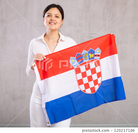 Middle-aged woman in casual clothes holds unfurled flag of Croatia in hands raised above head 120217186