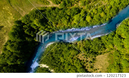A tranquil blue river meandering through dense, vibrant green forest. A tranquil blue river meandering through dense, vibrant green forest. 120217323