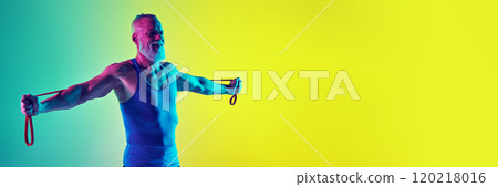 Strong hands. Elderly man with muscular body, in sportswear, training with resistance band against gradient green yellow background in neon light 120218016
