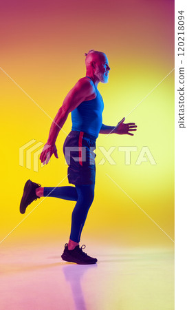 Full-length side view image of muscular elderly man in sportswear in motion, training against gradient yellow background in neon light Full-length side view image of muscular elderly man in sportswear in motion, training against gradient yellow background in neon light 120218094