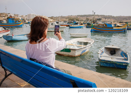 Woman traveler recording video in touristic fishing village Marsaxlokk in Malta 120218109