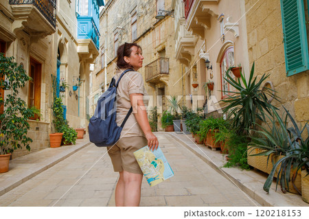 Woman tourist walking around Malta island with a paper map and backpack 120218153