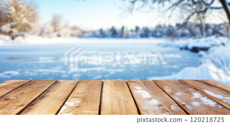 Beautiful blurred frozen lake in idyllic winter landscape, empty wooden planks in foreground, copy space on wooden table, 120218725