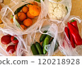 Farm market vegetables and fruits. Fresh natural cucumbers, tomatoes, cauliflowers and red peppers in plastic bags on the kitchen table. 120218928