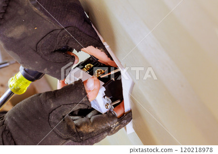 In this task, electrician connects installs electrical outlets sockets on exterior facade of building In this task, electrician connects installs electrical outlets sockets on exterior facade of building 120218978