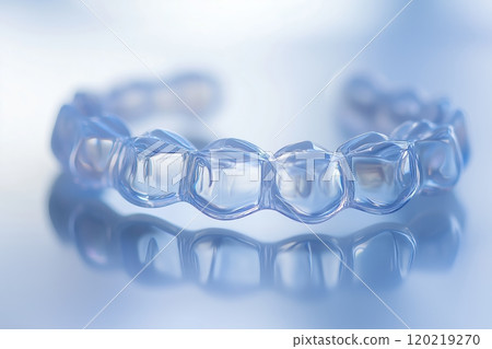 Invisible orthodontic teeth alignment braces reflecting on glass table Invisible orthodontic teeth alignment braces reflecting on glass table 120219270