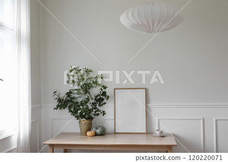 Elegant Scandinavian living room interior, home office. Wooden poster, picture frame mockup on table. Green branches in vase, pumpkins, cup of coffee. Textile lamp shade. Thanksgiving home decor. Elegant Scandinavian living room interior, home office. Wooden poster, picture frame mockup on table. Green branches in vase, pumpkins, cup of coffee. Textile lamp shade. Thanksgiving home decor. 120220071
