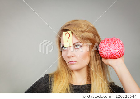 Woman thinking and holding fake brain Woman thinking and holding fake brain 120220544