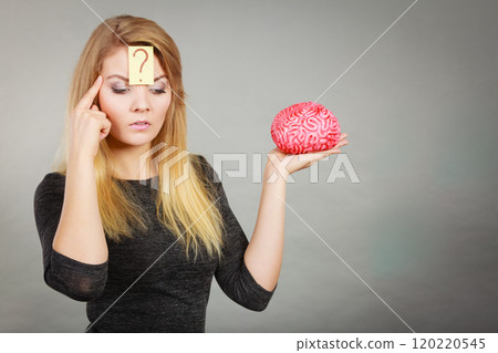 Woman thinking and holding fake brain Woman thinking and holding fake brain 120220545