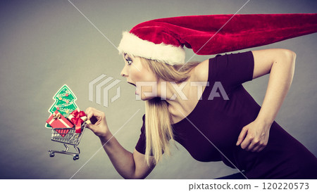 Santa woman holding shopping cart with christmas gifts Santa woman holding shopping cart with christmas gifts 120220573
