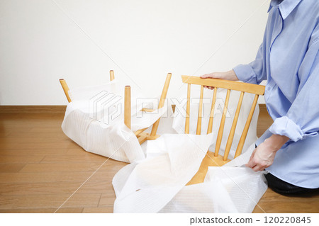A woman unpacking a chair purchased online 120220845
