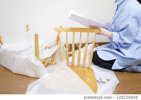 一位女士閱讀說明書來組裝她在網路上購買的椅子。 120220848