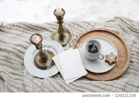 Christmas still life cup of hot drink coffee, gingebread cookie on plate. Blank greeting card mockup. Vintage brass candleholders. Winter banner. Blurred snow background. Flatlay, top view, copyspace 120221220