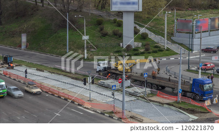 Loader crane for loading and unloading tram rails from truck which stands on a road construction site aerial timelapse 120221870