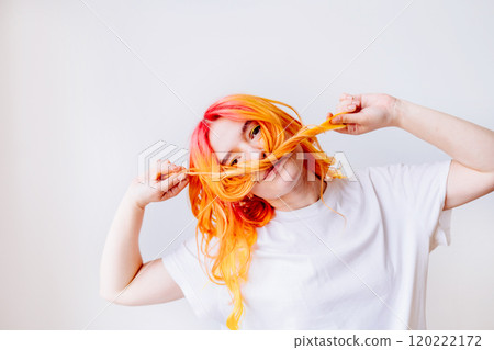 Young female adult with bright orange and red hair playfully posing indoors. Young girl twists hair into mustache, fun and creativity. Expression of individuality, artistic flair, spirited moment. Young female adult with bright orange and red hair playfully posing indoors. Young girl twists hair into mustache, fun and creativity. Expression of individuality, artistic flair, spirited moment. 120222172
