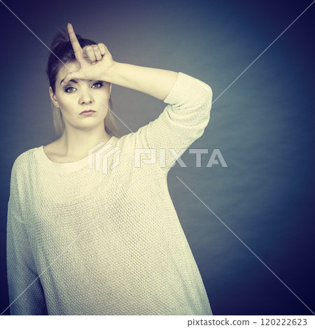 Woman showing loser gesture with L on forehead 120222623