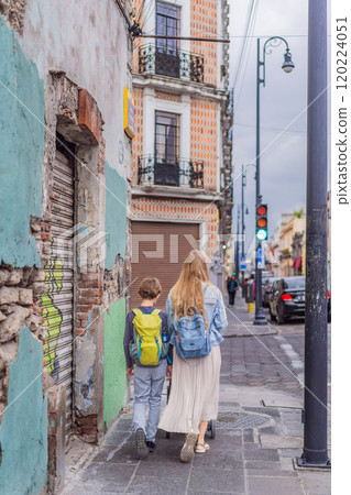 Mother tourist with her toddler and teenage sons walking through the colorful colonial streets of Puebla, Mexico. Travel, cultural exploration, and vibrant architecture concept Mother tourist with her toddler and teenage sons walking through the colorful colonial streets of Puebla, Mexico. Travel, cultural exploration, and vibrant architecture concept 120224051