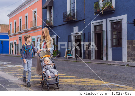 Mother tourist with her toddler and teenage sons walking through the colorful colonial streets of Puebla, Mexico. Travel, cultural exploration, and vibrant architecture concept Mother tourist with her toddler and teenage sons walking through the colorful colonial streets of Puebla, Mexico. Travel, cultural exploration, and vibrant architecture concept 120224053