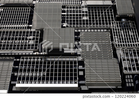 The wall of a modern building with randomly placed metal louvers of various designs and sizes The wall of a modern building with randomly placed metal louvers of various designs and sizes 120224060