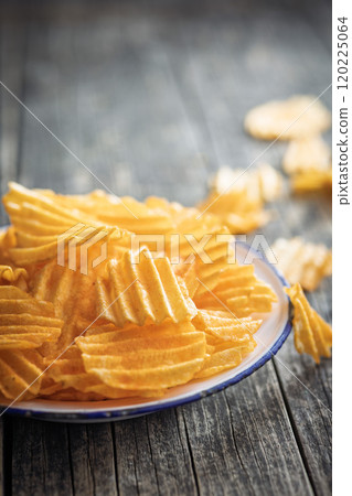 Crispy potato chips on plate on wooden table. Crispy potato chips on plate on wooden table. 120225064