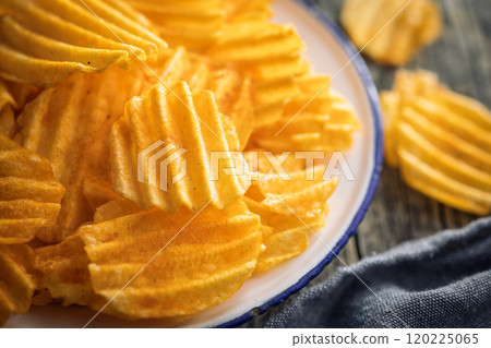 Crispy potato chips on plate on wooden table. Crispy potato chips on plate on wooden table. 120225065
