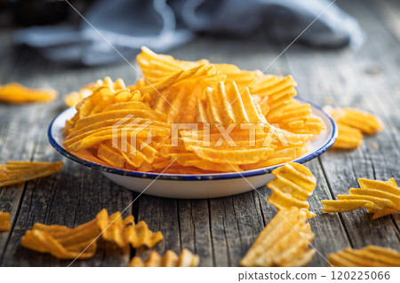 Crispy potato chips on plate on wooden table. Crispy potato chips on plate on wooden table. 120225066