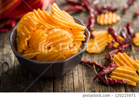 Crispy potato chips in bowl on wooden table. 120225071